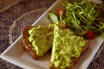 Tostadas con aguacate pisado y ensalada de hojas verdes.