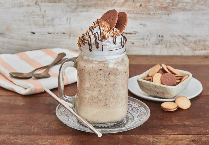 Jarra de café frio con crema arriba, dos galletas y salsa de chocolate.