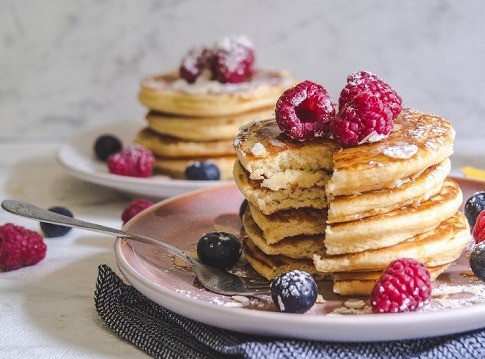 Dos torres de pancakes con frambruesas y arandanos.